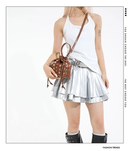 Detail of dark brown drawstring bucket bag featuring silver rivets and metal hardware