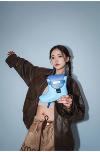 Detailed view of sky blue rain boot shaped crossbody bag worn by a fashion model