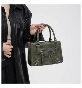 Detail shot of the dark green leather bag with silver rivets and zippers in motorcycle style