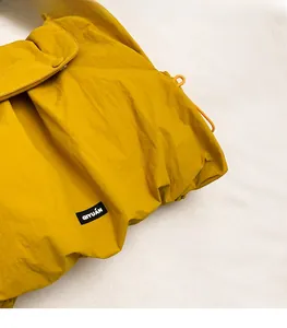 Close-up of yellow shoulder bag featuring nylon crinkle texture and orange drawstring detail