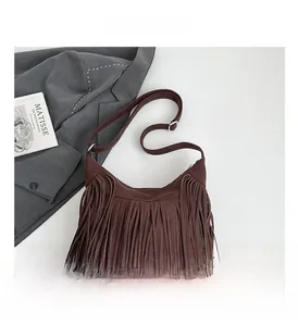 Close-up of dark brown fringe tote bag with adjustable strap on a minimalist background