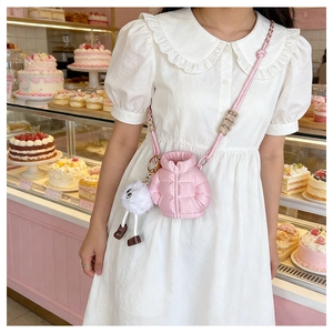 Pink quilted down puffer crossbody bag shown with cute white plush mascot detail