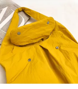 Detailed view of the yellow tote bag featuring a polished silver magnetic metal buckle closure