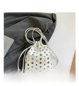 Detailed view of white leather bucket bag with silver rivets and drawstring closure