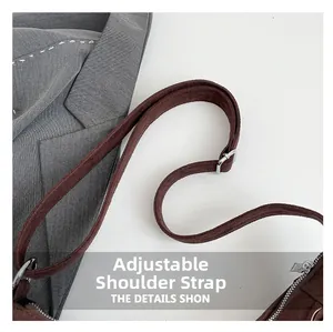 Detail of adjustable shoulder strap with silver buckle on brown suede crossbody bag