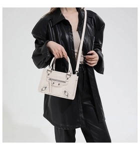 Detail of white motorcycle bag with silver rivets and tassels on leather jacket