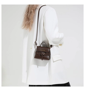 Détail du mini sac bandoulière marron foncé sur blazer blanc avec bandoulière réglable