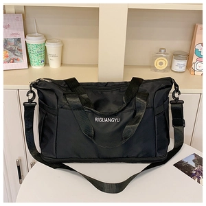 Close-up of black travel bag with sturdy handles, side pocket, and adjustable shoulder strap