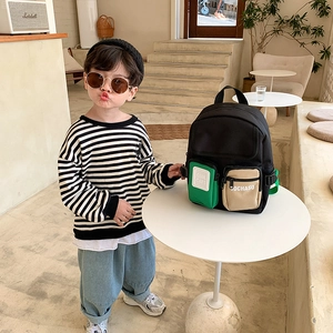 Kids color-block backpack with vibrant green straps shown on a child in a home setting