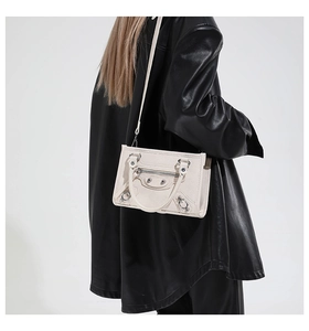 Detail view of a white studded motorcycle handbag with silver rivets and textured leather