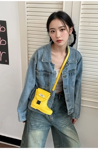 Close-up of a creative yellow rain boot shaped crossbody bag with branded label