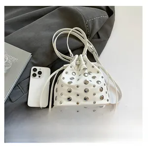 Top view of white bucket bag with silver studs and drawstring on dark grey suit fabric