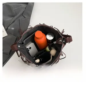 Brown suede crossbody bag with long fringes showing large interior storage capacity