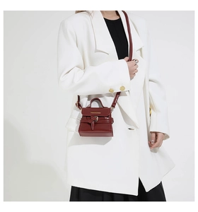 Détail du mini sac bandoulière en cuir bordeaux avec boucle dorée et texte de mode
