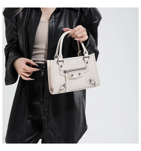 Close-up of cream motorcycle handbag featuring silver rivets and zip details