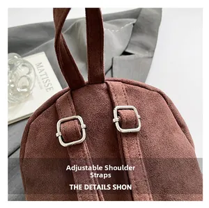 Detail view of the brown suede backpack featuring an adjustable strap with silver buckle