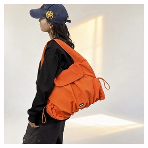 Detail of orange drawstring tote bag featuring lightweight nylon fabric and wide strap