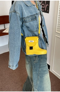 Detail of yellow rain boot shaped crossbody bag with black handle and shoulder strap
