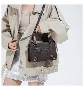 Detail of dark brown pebble leather handbag featuring vintage metal rivets and tassels