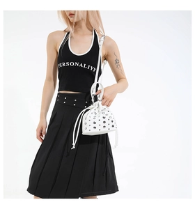Detail of white drawstring bucket bag with silver rivet studs and a thin shoulder strap