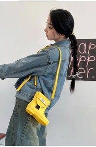 Detailed view of yellow rain boot shaped crossbody bag worn by model on casual outfit