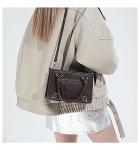 Detail of dark brown retro baguette bag with silver studs and adjustable shoulder strap