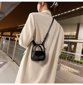 Detail view of a black leather mini crossbody bag with top handles shown in street photography