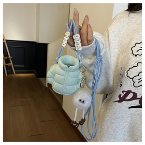 Detail of light blue puffer down jacket style mini bag with plush cartoon character charm