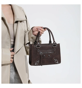 Detailed side view of a dark brown litchi texture leather satchel with silver rivets
