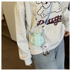 Detail of light blue puffer mini bag with cute long-legged plush ball charm on crossbody strap
