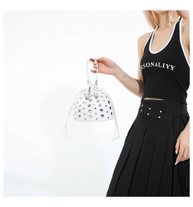 Detail of white leather bucket bag with silver metal studs and drawstring closure