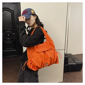 Detail of orange drawstring tote bag with water-repellent fabric and citywalk label