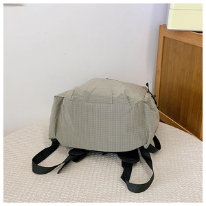 Detail des salbeigrünen Nylon-Rucksacks mit Karomuster und schwarzen Gurt-Schnallen
