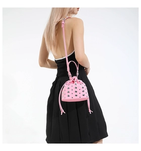 Pink drawstring bucket bag with silver rivets and shoulder strap on model