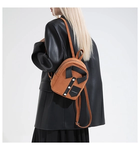 Detail of orange shirt-style mini suede backpack worn with a black oversized leather blazer