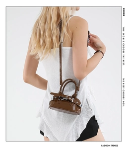 Detail of dark brown glossy shell bag with silver buckle and sleek shoulder strap