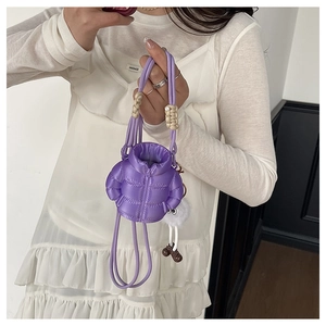 Detail of purple puffer jacket style mini bag with quilted texture and plush charm