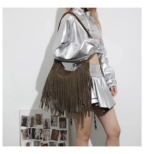 Detail of dark brown suede fringe tote bag with long bohemian tassels on solid surface