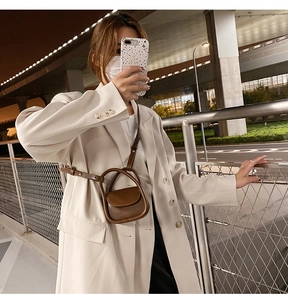 Detail of dark brown leather mini waist bag worn over a beige suit for a chic urban look