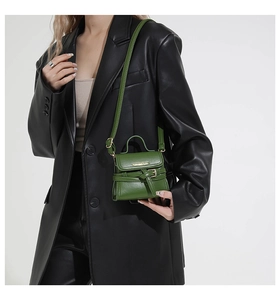 Detailed close-up of dark green leather handbag featuring Fashion Bags embossed metal logo