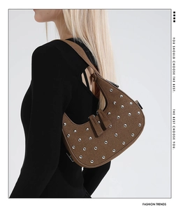 Brown suede crescent bag with silver rivet studs worn by model over shoulder