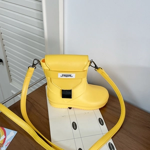 Detail of yellow boot-shaped crossbody bag with adjustable strap and brand logo