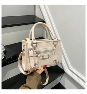 Detail of cream motorcycle handbag with metal studs and decorative zipper straps