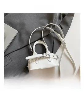 Detail of white patent leather handbag with silver metallic buckle and glossy finish