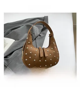 Close-up of brown suede moon bag with silver rivets and vintage punk style aesthetic