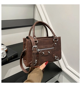 Detail of dark brown rivet motorcycle bag featuring silver hardware and textured faux leather