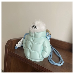 Close-up of a blue down jacket style mini bag with a plush monster on a wooden shelf