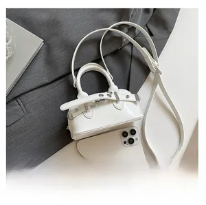 Mini sac coquille en cuir verni blanc avec smartphone pour comparer la taille