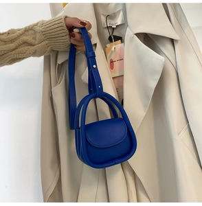 Detail of royal blue mini handbag with smooth faux leather texture on beige trench coat