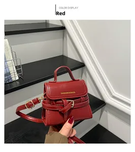 Detailed view of red mini shoulder bag with gold lettering and decorative buckle